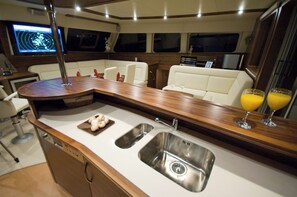 Interior de un yate con cocina, zona de estar con vistas y panel de control.