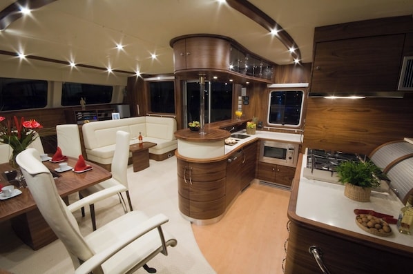 A compact, well-lit interior with a dining area, seating, a kitchen, and a large window.