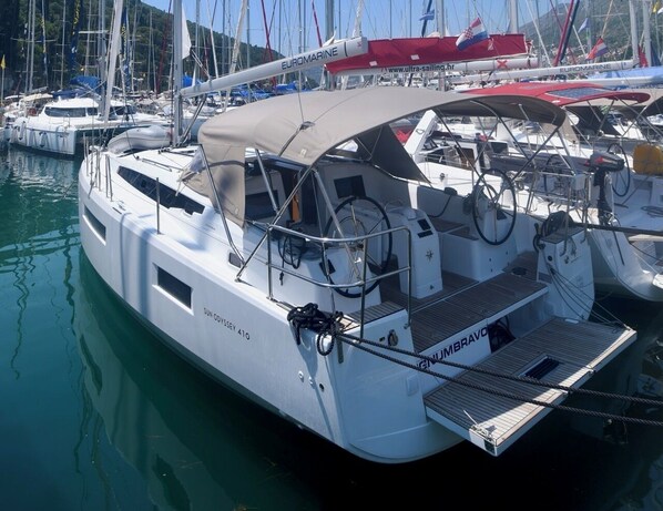 Un yate blanco llamado SUN ODYSSEY 410 atracado en un puerto deportivo con varios otros barcos.