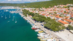 A coastal town with a marina, residential buildings, and a hilly backdrop. - Sun-Kissed Sailing Adventure in Northern Croatia (Punat)