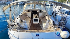 A boat named 'Jugo' with a steering wheel, a small control panel, and a wooden deck. - Sun-Kissed Sailing Adventure in Northern Croatia (Punat)