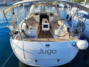 A boat named 'Jugo' with a steering wheel, a small control panel, and a wooden deck. - Sun-Kissed Sailing Adventure in Northern Croatia (Punat)