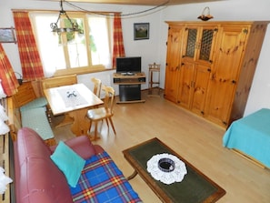 A cozy room with a wooden sofa, a small dining table, a television, and a cabinet. - Bolgen Appartement/Fewo, Dusche oder Bad, WC 4-Bettwohnung by Interhome (Zweisimmen)