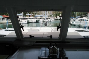 A boat's interior with a view of a marina, a teakettle on the table, and a railing. - Dubrovnik Delight: A Sun-Kissed Sailing Experience (Komolac)