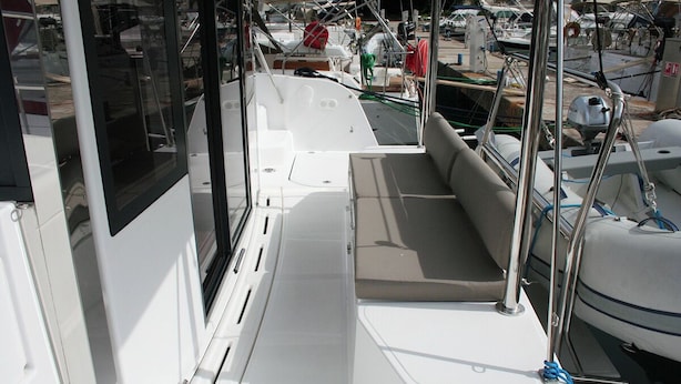 Ein Bootsdeck mit Sitzgelegenheiten, einem Fenster und verschiedenen Schiffsausrüstungsgegenständen.