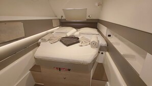 Ein kleines Zimmer mit einem Einzelbett, einem kleinen Tisch und einer Deckenleuchte.