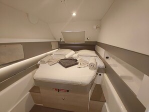 Ett litet rum med en enkel säng, ett litet bord och en taklampa.