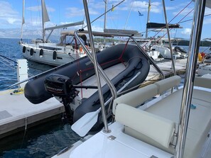 Ein Boot liegt in einer Marina festgemacht, mit einem Mercury Außenbordmotor, einer weißen, gepolsterten Sitzgelegenheit und einem Rettungsring.