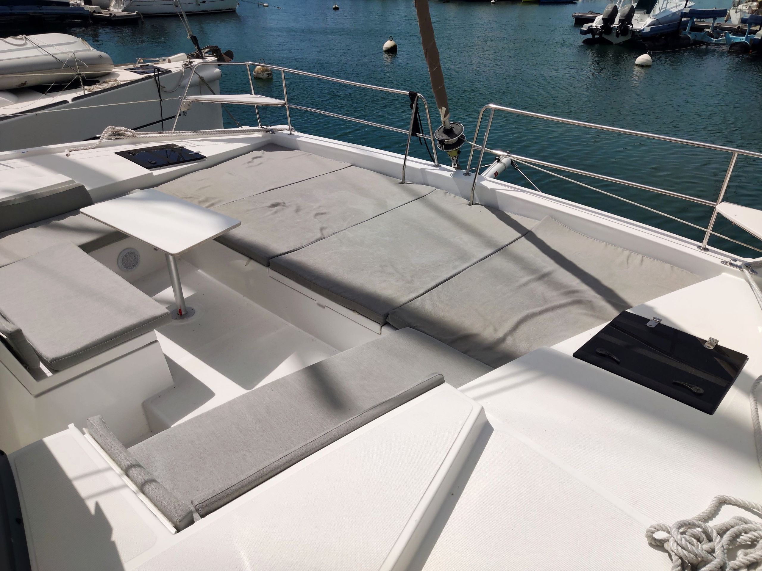 A boat deck with seating areas, a table, and a view of the marina.