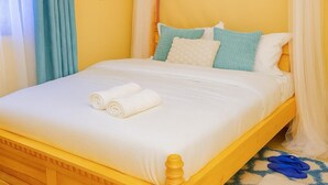 Ein Bett mit weißer Bettwäsche, gerollten Handtüchern, einem Holz-Kopfteil und einem gemusterten Teppich.