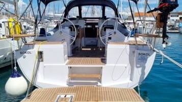 A sailboat with a covered deck, a steering wheel, and a winch.