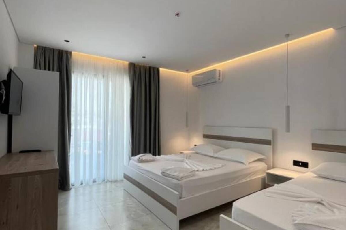Ein modernes Hotelzimmer mit zwei Betten, einem Schreibtisch und einem Fernseher.