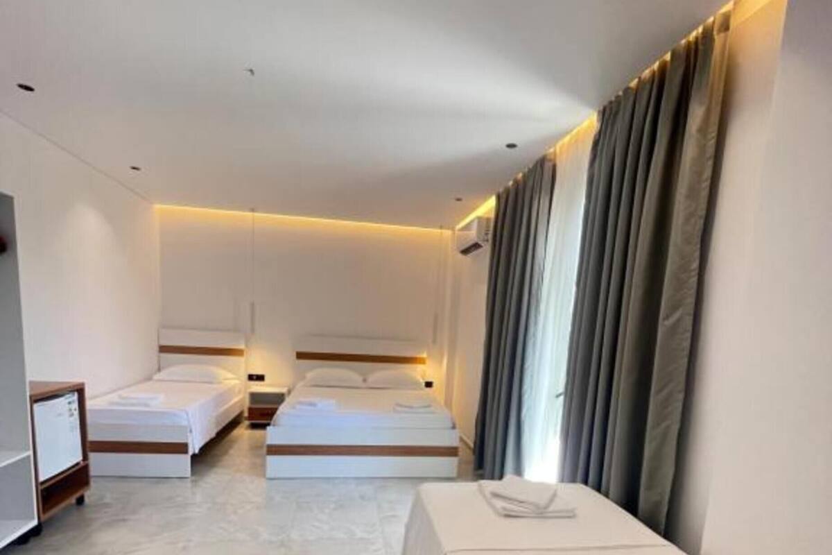 Ein Hotelzimmer mit zwei Einzelbetten, einem kleinen Tisch, einem Fernseher und einem Kleiderschrank.