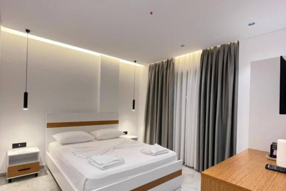 Ein modernes Schlafzimmer mit einem großen Bett, Nachttischen, einem Holztisch und einem Fernseher.
