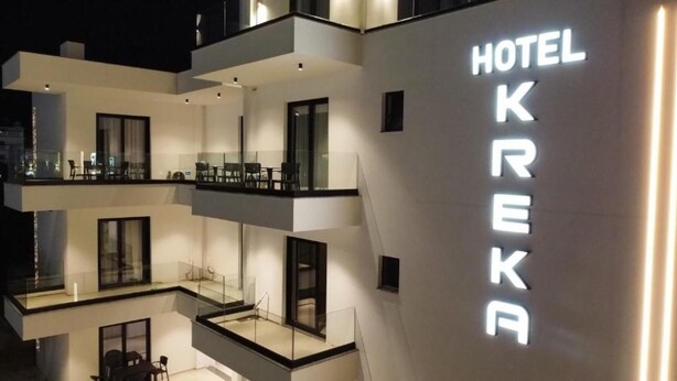 Un hotel de varios pisos con un llamativo letrero 'HOTEL KREKA', balcones y un diseño arquitectónico moderno.