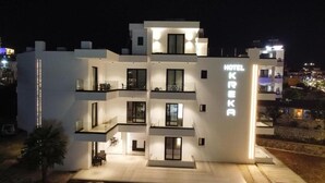 Un hotel moderno con varios balcones, un letrero llamativo y una fachada bien iluminada.