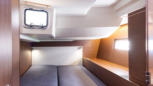 A compact RV interior with a small window, a bench, and a storage cabinet. - Sun-Kissed Sailing Adventure in the Ionian Islands, Lefkada (Lefkada)