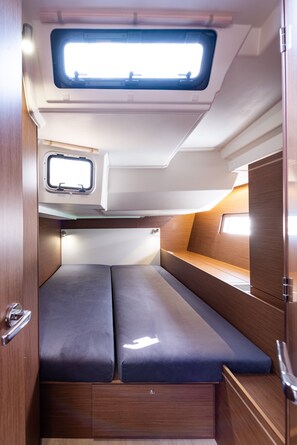 A compact RV interior with a small window, a bench, and a storage cabinet. - Sun-Kissed Sailing Adventure in the Ionian Islands, Lefkada (Lefkada)