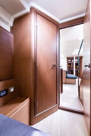 A modern interior with a wooden wardrobe, a small seating area, and a visible kitchen area. - Sun-Kissed Sailing Adventure in the Ionian Islands, Lefkada (Lefkada)