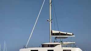 Un yate grande con casco blanco, múltiples ventanas y un mástil.