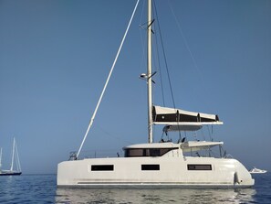 Eine große Yacht mit weißem Rumpf, mehreren Fenstern und einem Mast.