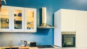Eine moderne Küche mit weißen Schränken, einer blauen Akzentwand, einem gelben Stuhl und einer Edelstahl-Dunstabzugshaube.