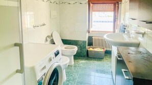 Ein kleines Badezimmer mit Waschmaschine, Toilette und Waschbecken.
