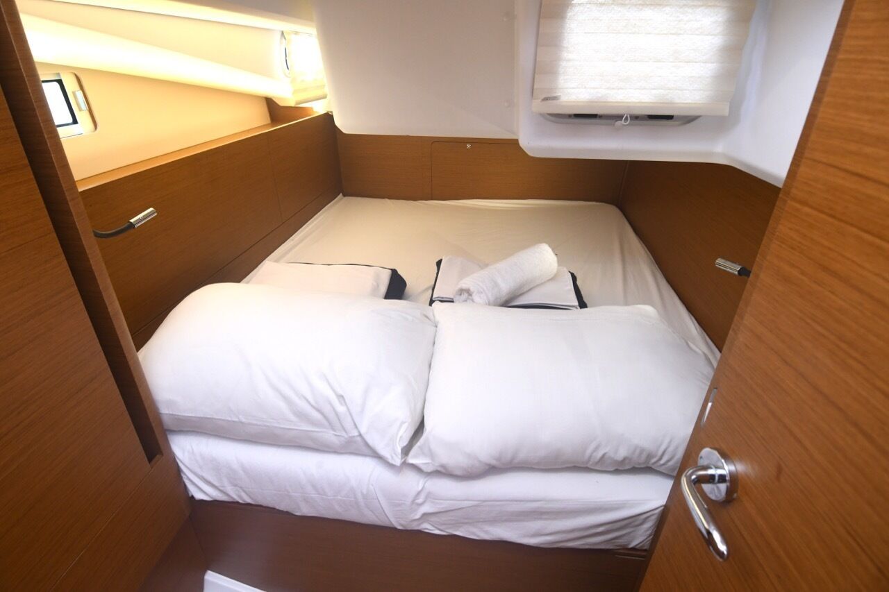 A compact, single-bed cabin with a wooden finish, a small window with a blind, and a door with a handle.