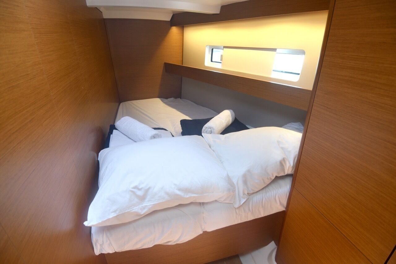 Une pièce de taille modeste, meublée en bois, avec un lit simple, une table de chevet et une petite fenêtre.