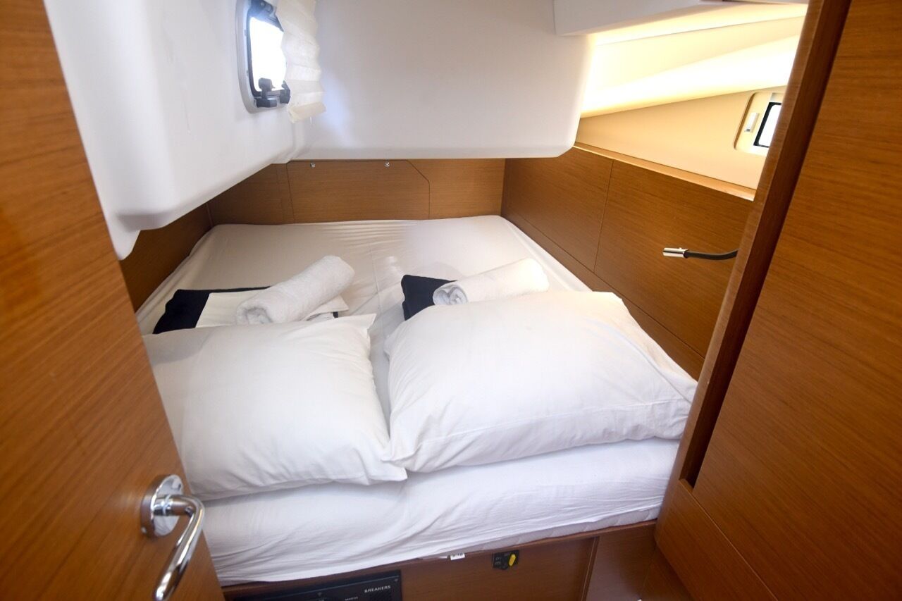 Ein kleines Zimmer mit einem Einzelbett, einem Holzkopfteil, einem Nachttisch und einer eingebauten Lampe.