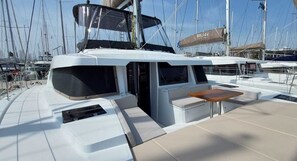 Ein Yachttdeck mit einer Sitzecke, einem kleinen Tisch und einem überdachten Bereich.