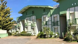 Un edificio con facciata verde, numerose finestre e un parcheggio.