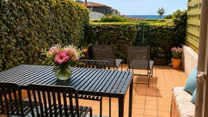 Una terrazza esterna con tavolo e sedie, un divano e una pianta in vaso.