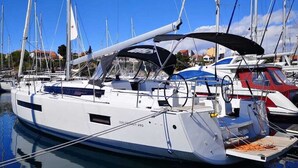 A marina with a white yacht docked, featuring a covered deck, a steering wheel, and a name 'SUN COASTER 490'.