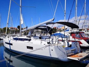 A marina with a white yacht docked, featuring a covered deck, a steering wheel, and a name 'SUN COASTER 490'.