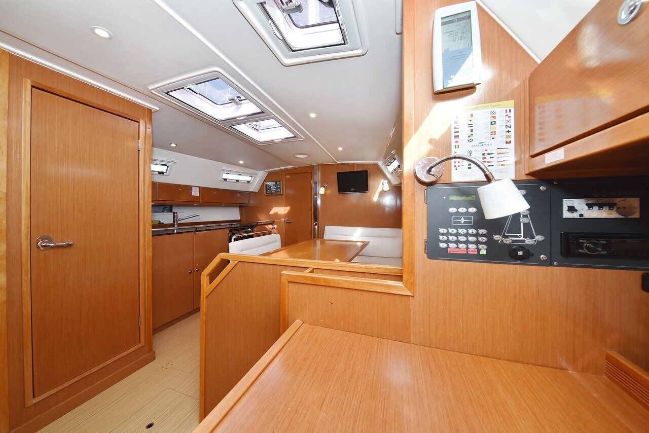 A compact kitchen with wooden cabinets, a small dining area, and a control panel with various buttons and a screen.