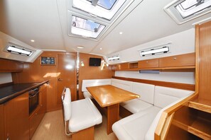 A compact galley with a wooden table and white cushioned seating, skylights, and built-in cabinetry. - Sun-Kissed Sailing Adventure in Zadar, Croatia (Zadar)