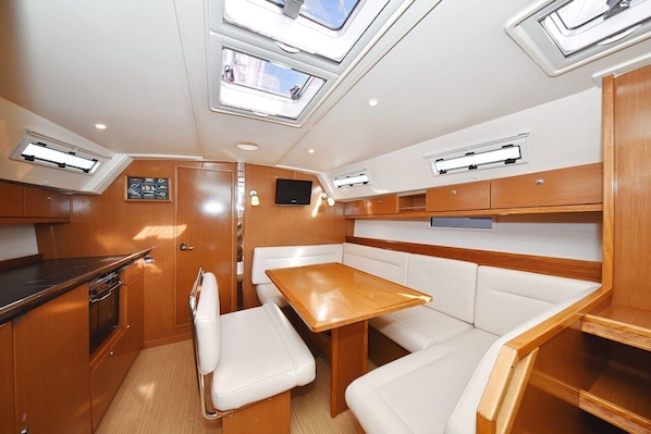 A compact galley with a wooden table and white cushioned seating, skylights, and built-in cabinetry. - Sun-Kissed Sailing Adventure in Zadar, Croatia (Zadar)