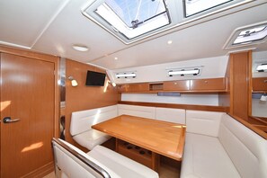 A compact interior with a wooden table, cushioned seating, a television, and skylights. - Sun-Kissed Sailing Adventure in Zadar, Croatia (Zadar)