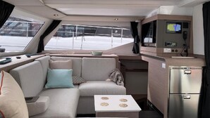En lyxig inredning i en yacht med en soffa, ett litet bord, ett köksområde och en kontrollpanel.