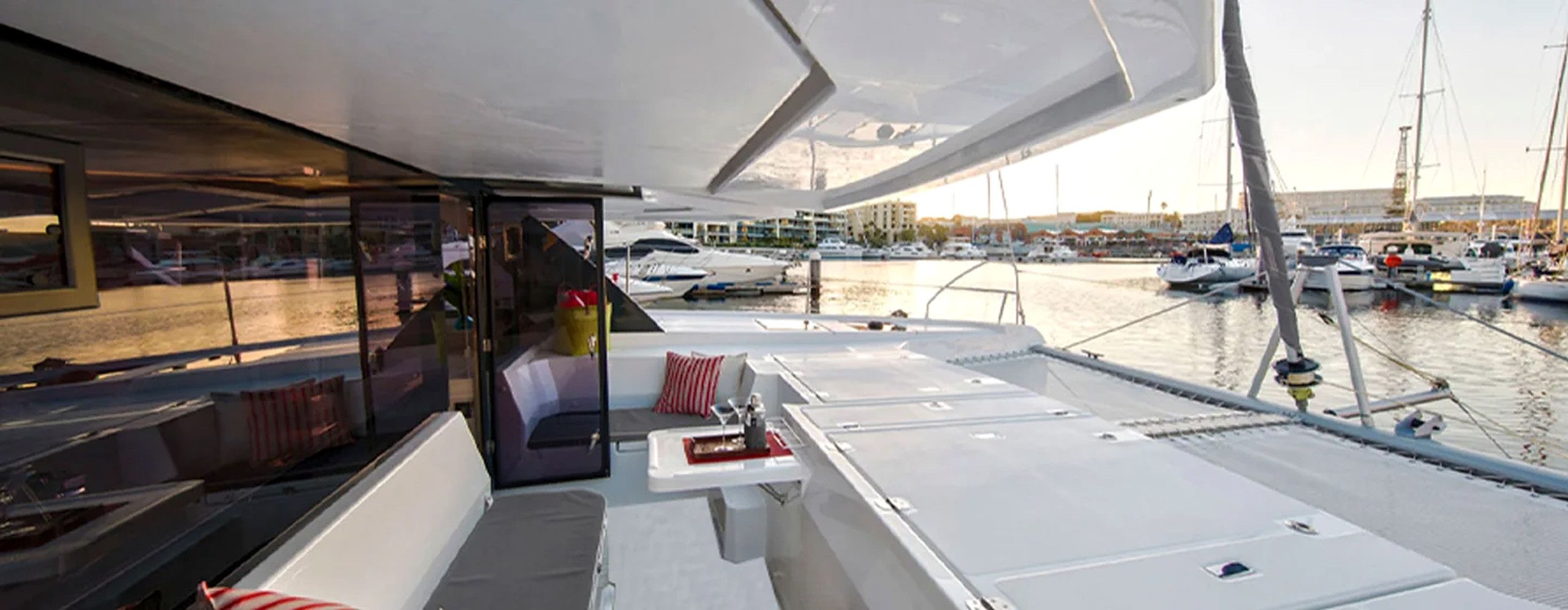 A boat deck with a seating area, a table with a red napkin, and a view of a marina with boats.