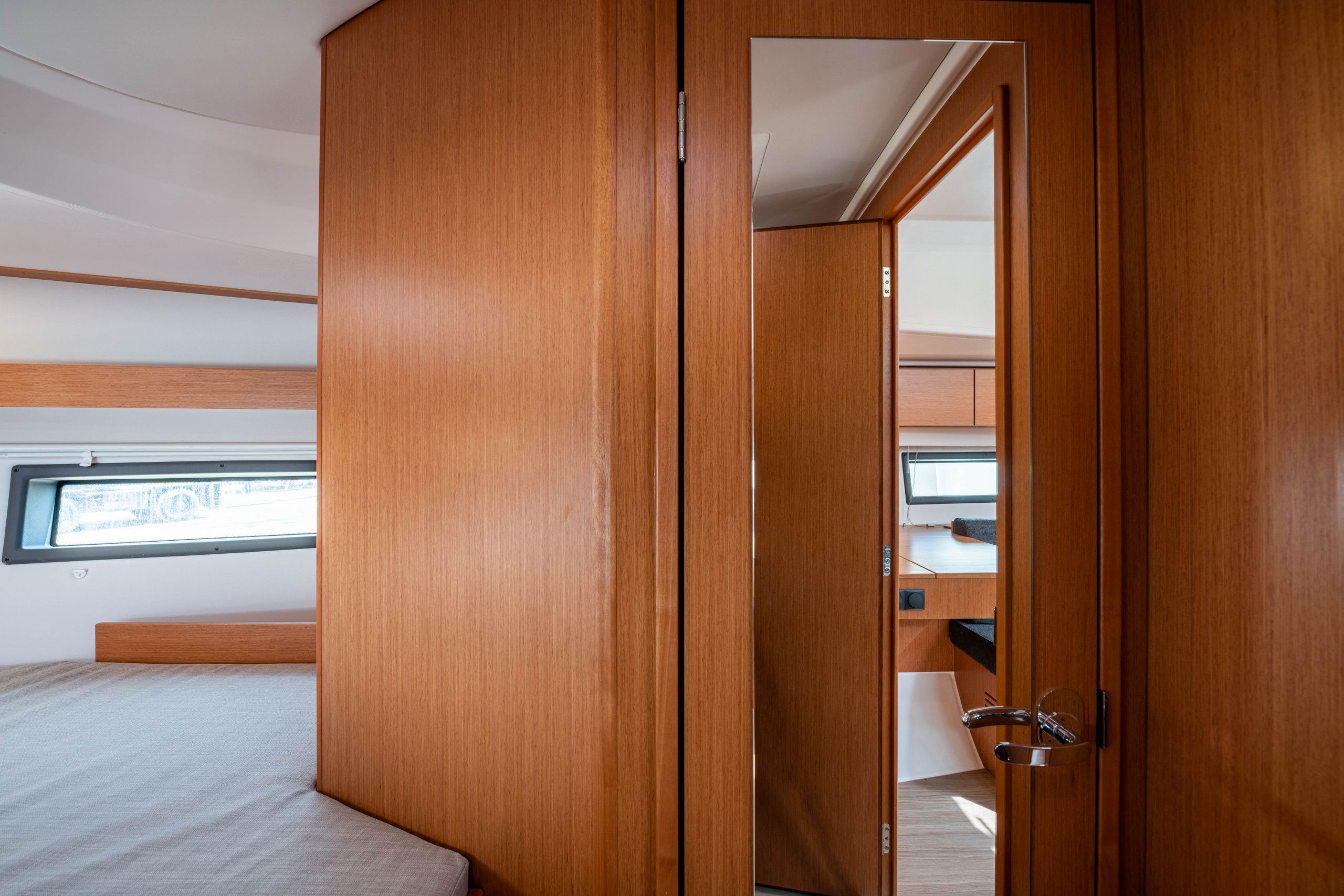 A compact room with a bed, a wooden wardrobe, and a small desk area.