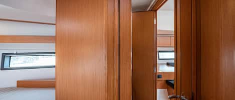 A compact room with a bed, a wooden wardrobe, and a small desk area.