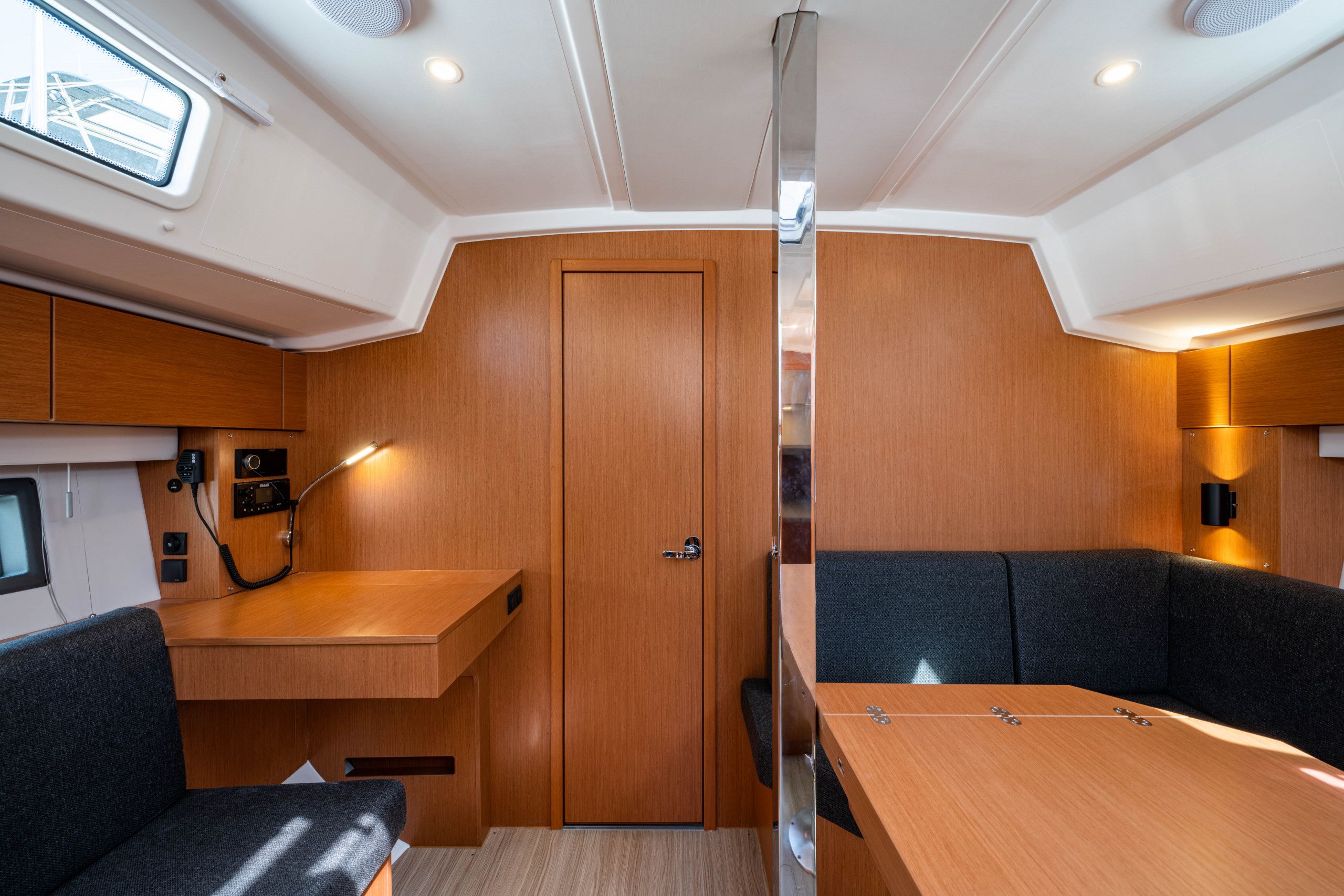 Un intérieur compact avec une porte en bois, une petite table, un banc et un luminaire fixé au mur.