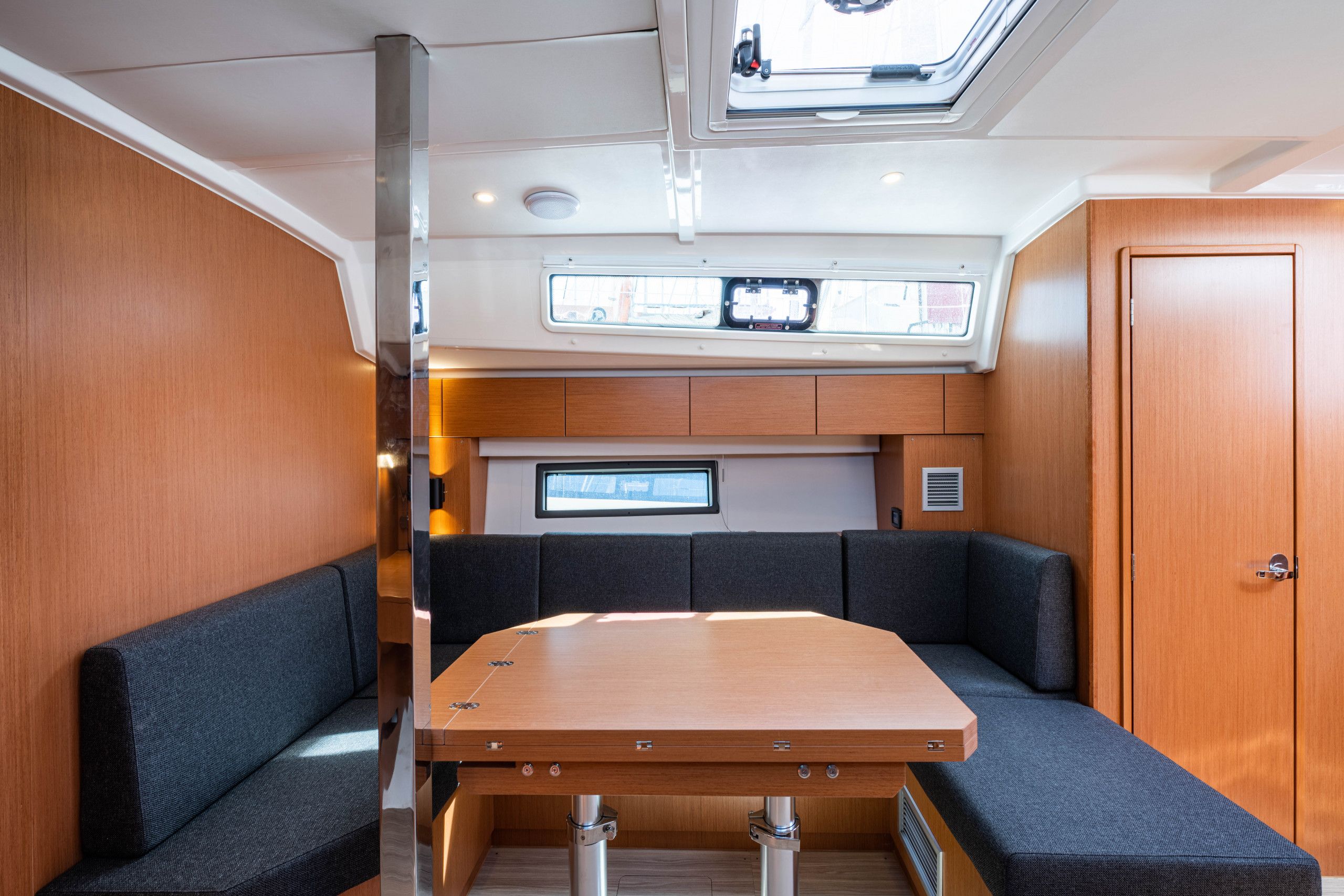 A compact interior with a wooden table, cushioned seating, a built-in TV, and a skylight.