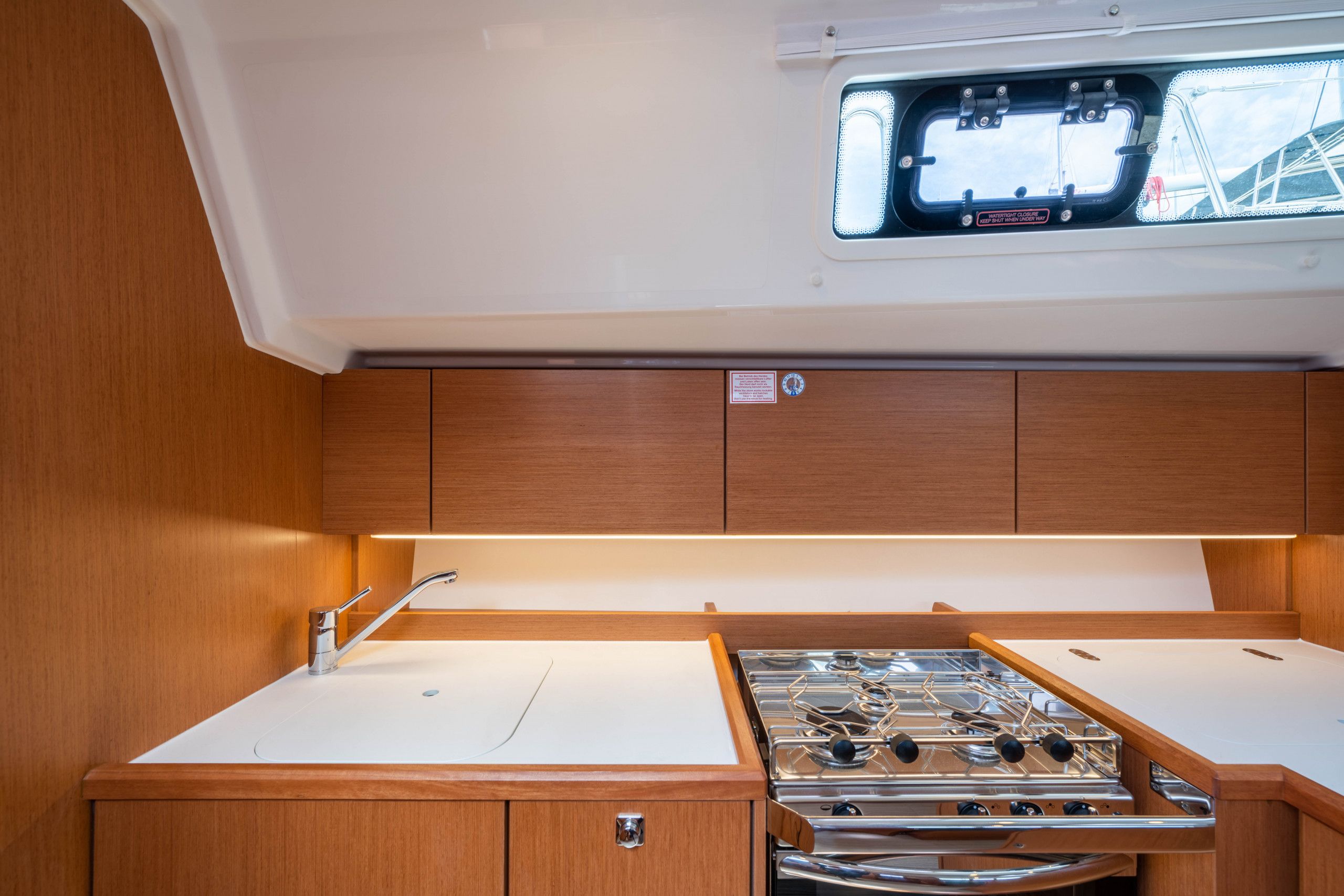 A compact kitchen with a sink, stove, and a window above the countertop.