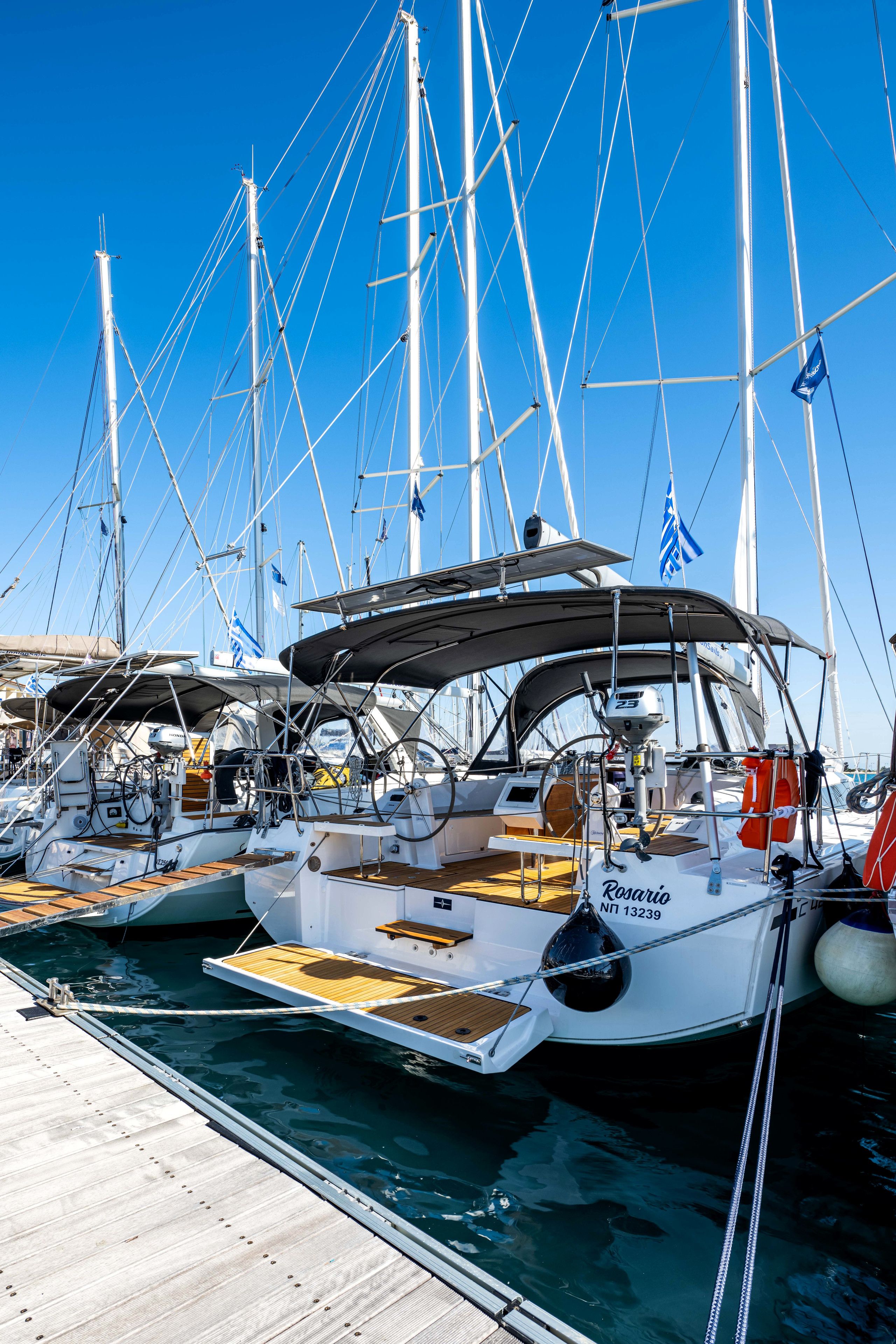 A marina with multiple sailboats docked, featuring wooden decks and white hulls.