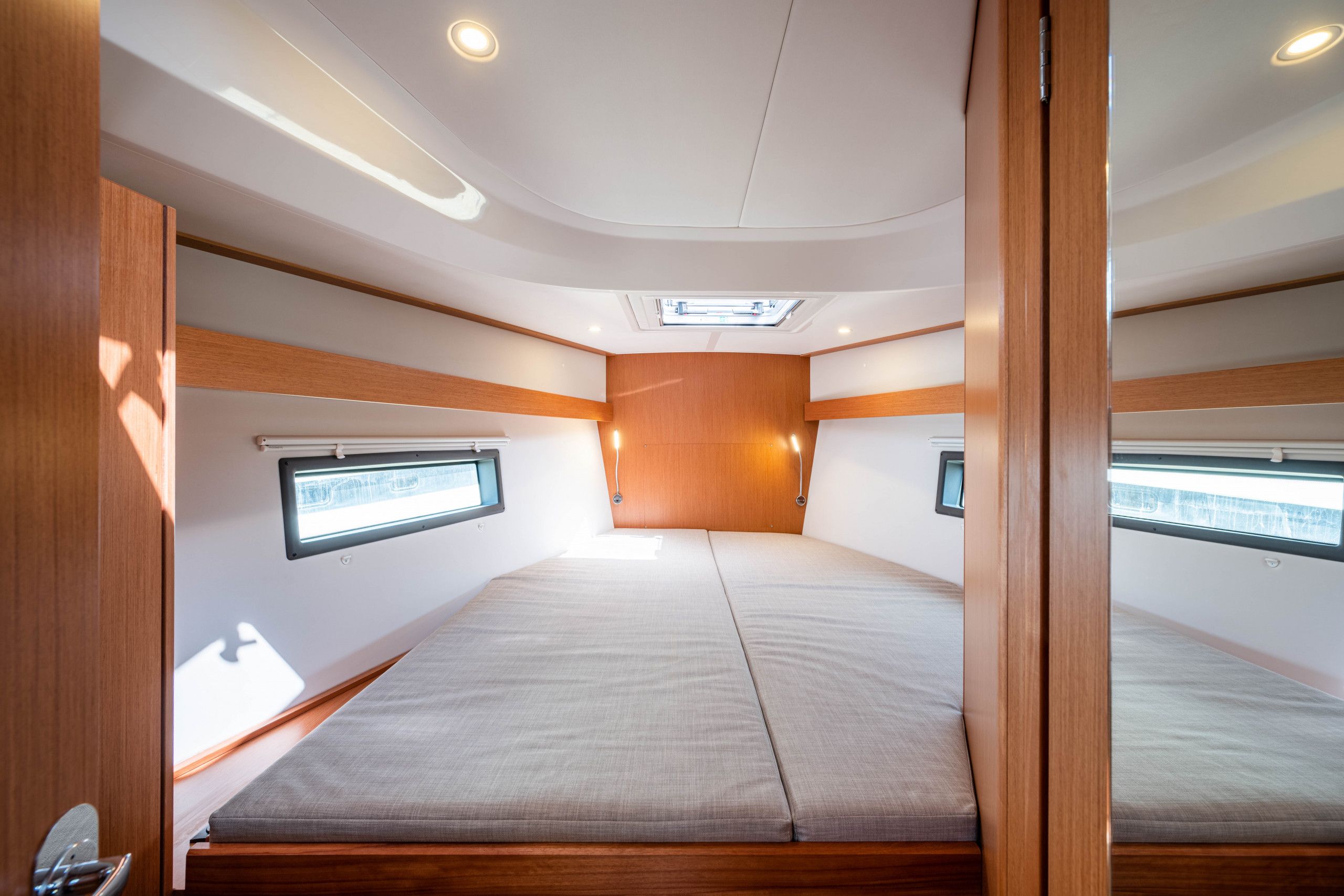 A compact, well-lit interior with a central bed, skylight, and built-in windows.