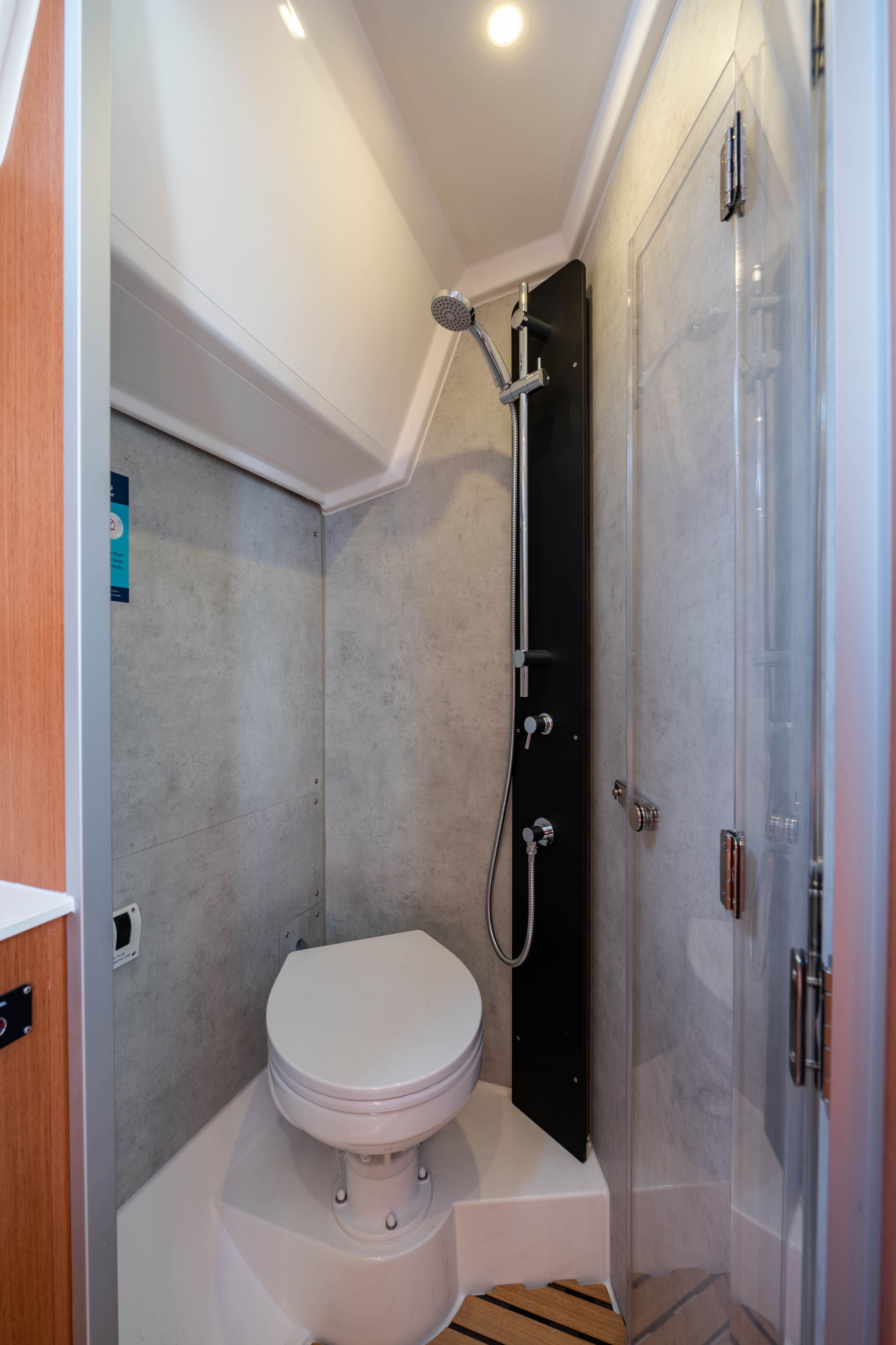 A compact bathroom with a toilet, shower, and a glass door.