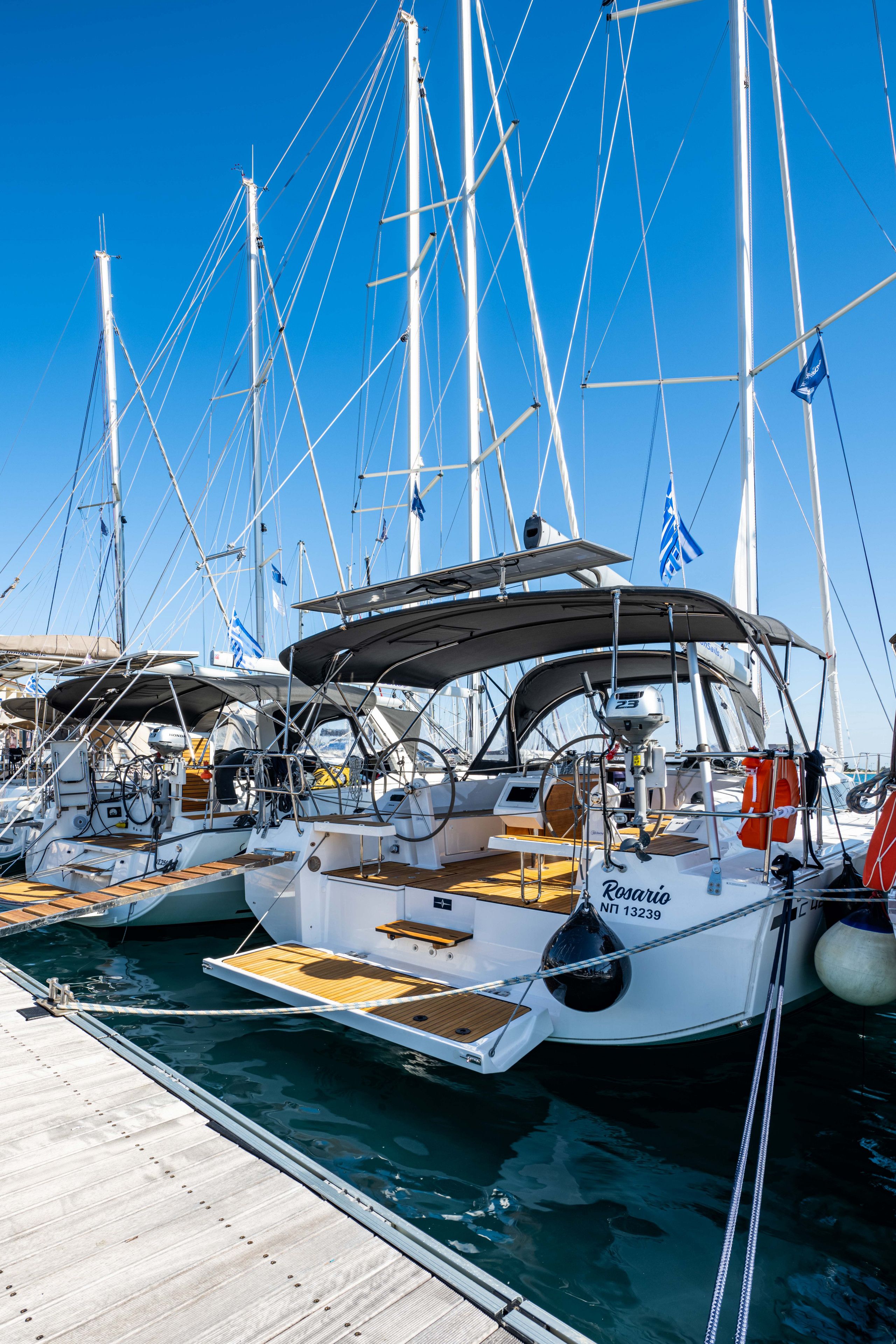 Ein Yachthafen mit mehreren Segelbooten an den Stegen, mit Holzdecks und weißen Rümpfen.
